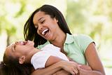 Woman and young girl outdoors embracing and laughing