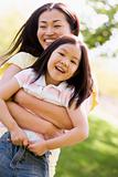 Woman and young girl outdoors embracing and smiling