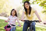 Woman and young girl on bikes outdoors smiling