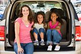 Woman with two young girls sitting in back of van smiling