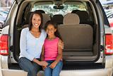 Woman with young girl sitting in back of van smiling
