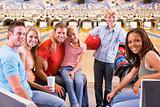 Family in bowling alley with two friends smiling