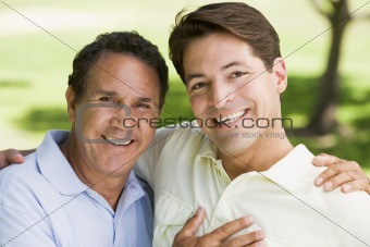 Two men outdoors embracing and smiling
