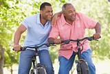 Two men on bikes outdoors smiling