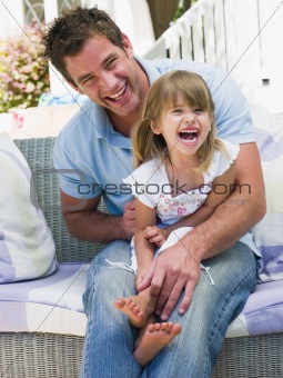 Man and young girl sitting on patio laughing