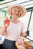 Woman in greenhouse holding cherry tomatoes smiling