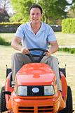 Man outdoors driving lawnmower smiling