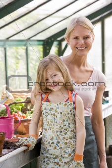 Young girl and woman in greenhouse smiling