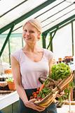 Woman in greenhouse holding basket of vegetables smiling