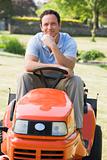 Man outdoors on lawnmower smiling