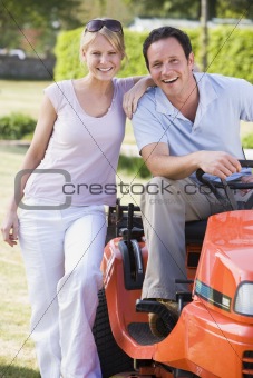 Couple outdoors with lawnmower smiling