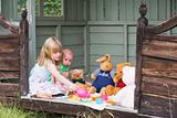 Young girl in shed with baby playing tea