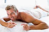 Man lying in bed pointing and smiling