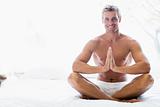 Man sitting on bed meditating and smiling