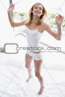 Woman jumping on bed smiling