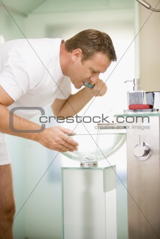 Man in bathroom brushing teeth