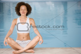 Woman sitting poolside doing yoga