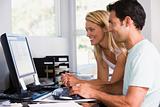 Couple in home office using computer and smiling