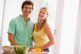 Couple in kitchen cutting up vegetables and smiling