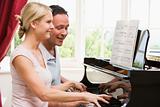 Couple playing piano and smiling