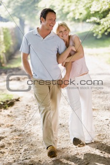 Couple walking outdoors arm in arm smiling