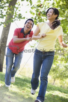 Couple running and being playful outdoors smiling