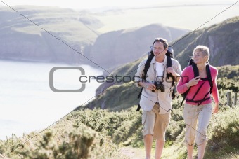 Couple on cliffside outdoors walking and smiling