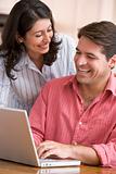 Couple in kitchen using laptop smiling