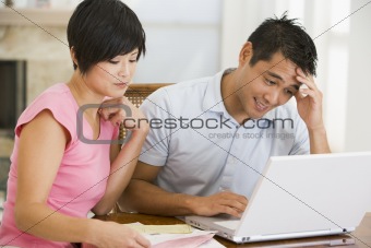 Couple in dining room with laptop looking unhappy