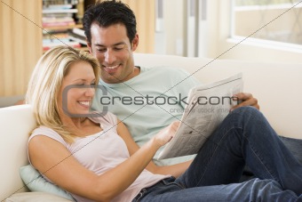 Couple in living room reading newspaper and smiling