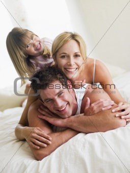 Family in bed playing and smiling