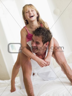 Man and young girl in bed playing and smiling