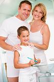 Couple in bathroom with young boy brushing teeth