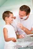 Man in bathroom putting shaving cream on young boy's nose