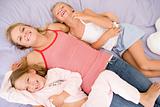 Woman and two young girls lying in bed playing and smiling