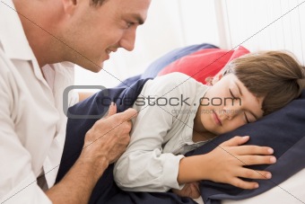 Man waking young boy in bed smiling