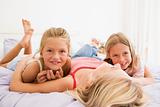 Woman lying in bed with two young girls smiling