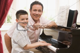 Man and young boy playing piano and smiling