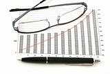 ballpoint pen and glasses on earning graphs