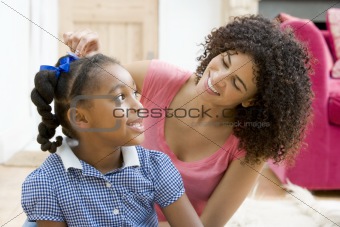 Woman in front hallway fixing young girl's hair and smiling