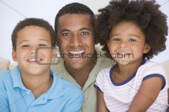 Man and two young children sitting in living room smiling