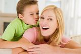 Young boy kissing smiling woman in living room