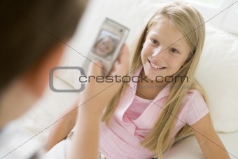 Young boy taking picture of smiling young girl with camera phone