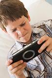 Young boy with handheld game indoors looking unhappy