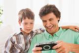 Man and young boy with handheld game smiling