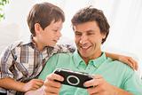 Man and young boy with handheld game smiling