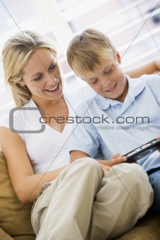 Woman and young boy in living room with handheld video game smil