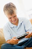 Young boy in living room with handheld video game smiling