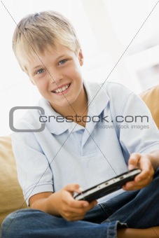 Young boy in living room with handheld video game smiling