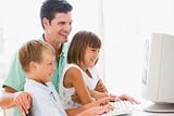 Man and two young children in home office with computer smiling